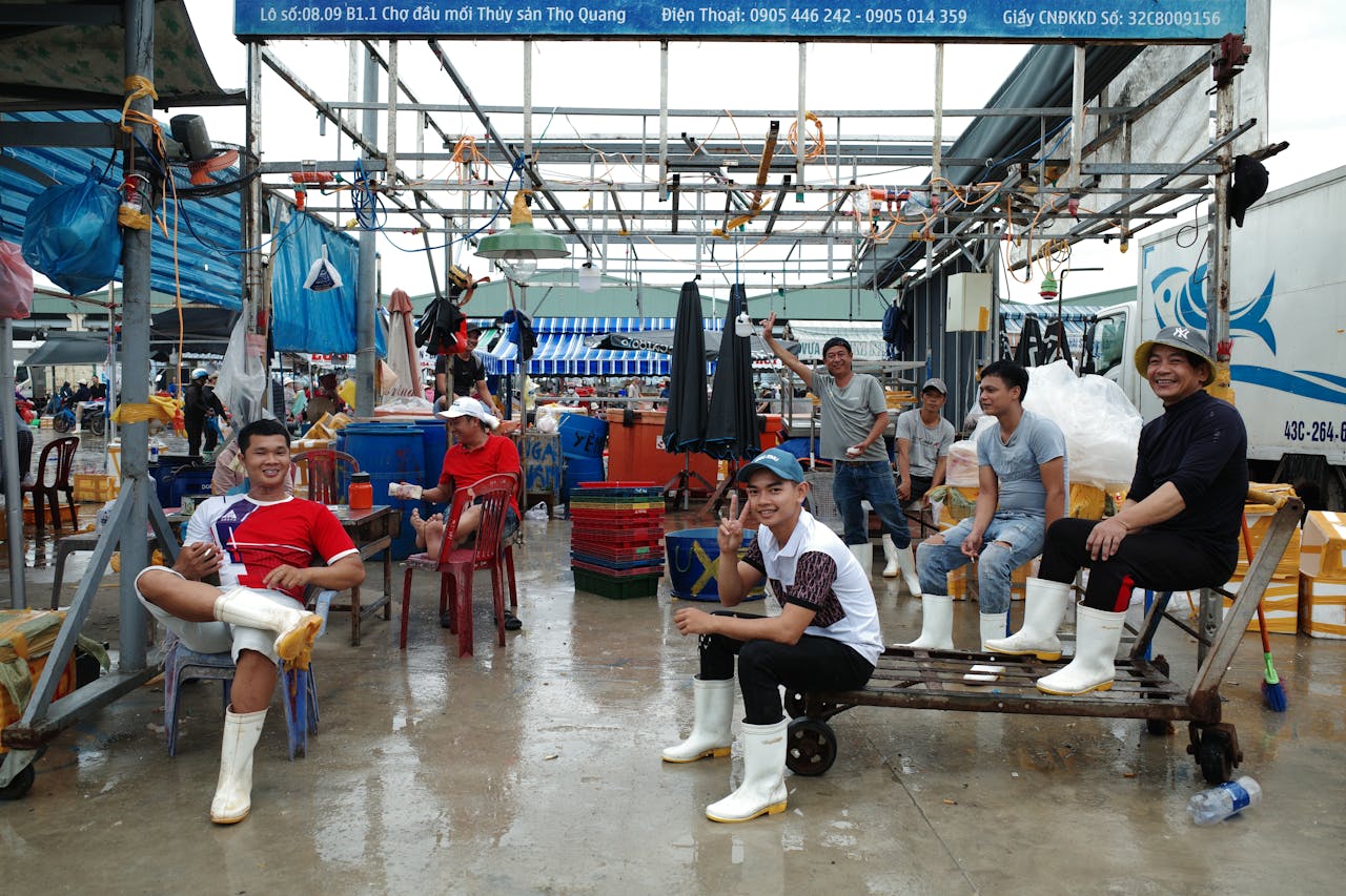 Group of men working and relaxing at a fish market in Đà Nẵng, Vietnam, amid vibrant market activity.